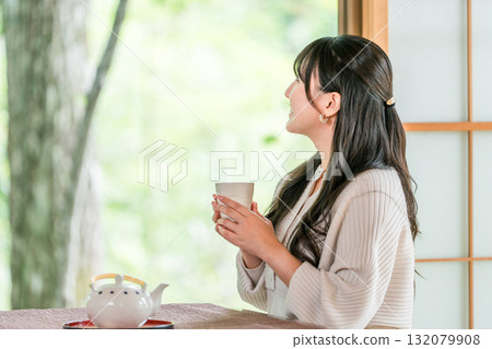 Ryokan, young Asian woman drinking tea in a Japanese-style room in a Japanese house Ryokan, young Asian woman drinking tea in a Japanese-style room in a Japanese house 132079908