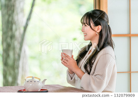 Ryokan, young Asian woman drinking tea in a Japanese-style room in a Japanese house 132079909