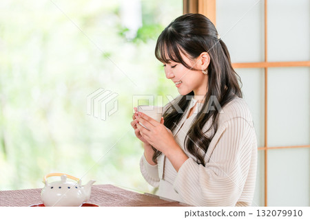 Ryokan, young Asian woman drinking tea in a Japanese-style room in a Japanese house 132079910