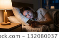 A woman relaxing in bed while looking at her smartphone 132080037