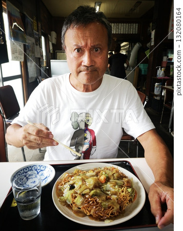 一位帥氣的男士在當地一家餐廳吃炒麵 132080164