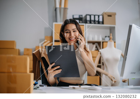 Asian woman prepares parcels and checks online orders on tablet and laptop for delivery online shopping and small business success Asian woman prepares parcels and checks online orders on tablet and laptop for delivery online shopping and small business success 132080232