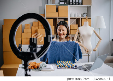 Asian woman prepares parcels and checks online orders on tablet and laptop for delivery online shopping and small business success 132080281