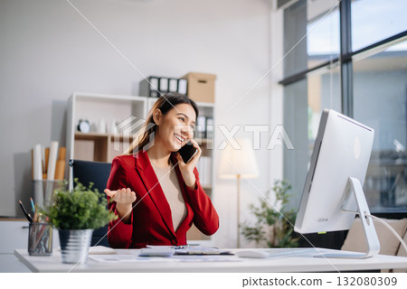 Young beautiful woman typing on tablet and laptop while sitting at the working white table in modern office Young beautiful woman typing on tablet and laptop while sitting at the working white table in modern office 132080309