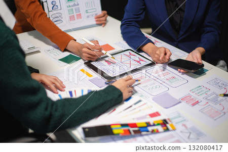 Close up view of UI developer team brainstorming on their project with laptop, smartphone and digital tablet. Close up view of UI developer team brainstorming on their project with laptop, smartphone and digital tablet. 132080417
