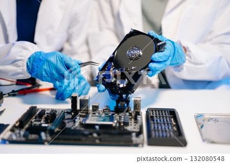 Hard disk drive on the technician's desk and a computer motherboard as a component. the concept of data, hardware 132080548