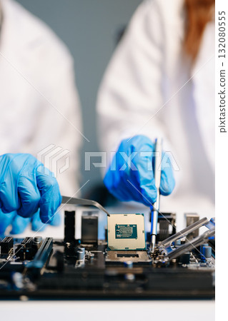The technician is putting the CPU on the socket of the computer motherboard. electronic engineering electronic repair, electronics measuring The technician is putting the CPU on the socket of the computer motherboard. electronic engineering electronic repair, electronics measuring 132080555
