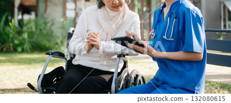 Elderly asian senior woman on wheelchair with Asian careful caregiver and encourage patient, walking in garden. Elderly asian senior woman on wheelchair with Asian careful caregiver and encourage patient, walking in garden. 132080615