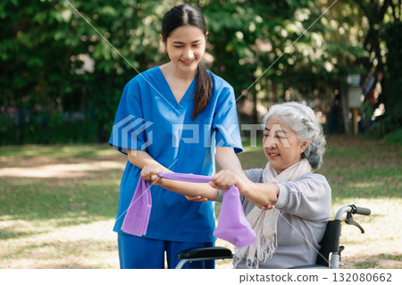 Asian physiotherapist helping elderly woman patient stretching arm during exercise correct with dumbbell in hand during training hand with patient Back problems in the garden. Asian physiotherapist helping elderly woman patient stretching arm during exercise correct with dumbbell in hand during training hand with patient Back problems in the garden. 132080662