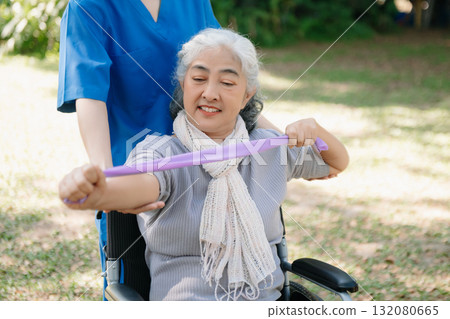 Asian physiotherapist helping elderly woman patient stretching arm during exercise correct with dumbbell in hand during training hand with patient Back problems in the garden. Asian physiotherapist helping elderly woman patient stretching arm during exercise correct with dumbbell in hand during training hand with patient Back problems in the garden. 132080665
