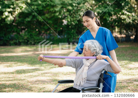 Asian physiotherapist helping elderly woman patient stretching arm during exercise correct with dumbbell in hand during training hand with patient Back problems in the garden. Asian physiotherapist helping elderly woman patient stretching arm during exercise correct with dumbbell in hand during training hand with patient Back problems in the garden. 132080666