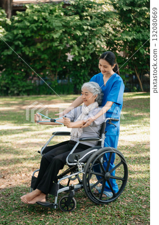 Asian physiotherapist helping elderly woman patient stretching arm during exercise correct with dumbbell in hand during training hand with patient Back problems in the garden. Asian physiotherapist helping elderly woman patient stretching arm during exercise correct with dumbbell in hand during training hand with patient Back problems in the garden. 132080669