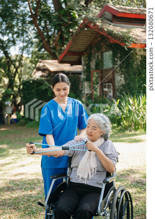 Asian physiotherapist helping elderly woman patient stretching arm during exercise correct with dumbbell in hand during training hand with patient Back problems in the garden. 132080671