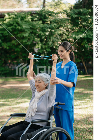 Asian physiotherapist helping elderly woman patient stretching arm during exercise correct with dumbbell in hand during training hand with patient Back problems in the garden. Asian physiotherapist helping elderly woman patient stretching arm during exercise correct with dumbbell in hand during training hand with patient Back problems in the garden. 132080674