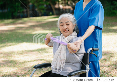 Asian physiotherapist helping elderly woman patient stretching arm during exercise correct with dumbbell in hand during training hand with patient Back problems in the garden. Asian physiotherapist helping elderly woman patient stretching arm during exercise correct with dumbbell in hand during training hand with patient Back problems in the garden. 132080756
