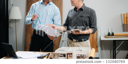 Two colleagues discussing data working and tablet, laptop with architectural project at construction site 132080769