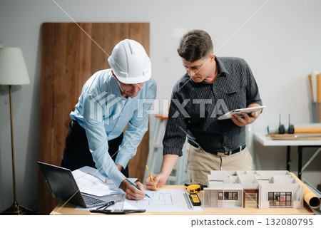 Two colleagues discussing data working and tablet, laptop with architectural project at construction site 132080795