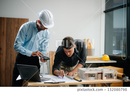 Contractor and architect looking at plan, tablet, laptop and talking about working on big project. 132080798