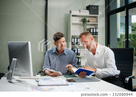 Two business workers talking on the smartphone and using laptop 132080944