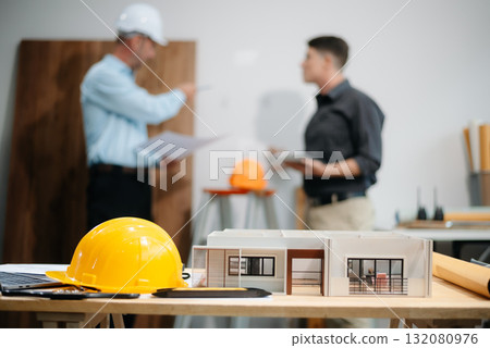 Engineer desk with object paper and tablet with blurry engineer teamwork hardworking to consults about their building project. 132080976