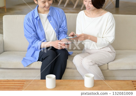 A Japanese woman sitting on a sofa and holding a smartphone 132081009
