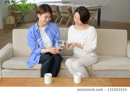 A Japanese woman sitting on a sofa and holding a smartphone A Japanese woman sitting on a sofa and holding a smartphone 132081010
