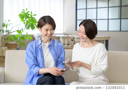 A Japanese woman sitting on a sofa and holding a smartphone 132081011