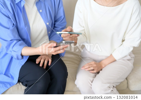 A Japanese woman sitting on a sofa and holding a smartphone A Japanese woman sitting on a sofa and holding a smartphone 132081014