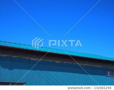A tin-walled storage shed and blue sky in a winter field 132081298