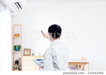 A man in work clothes checking the operation of an air conditioner A man in work clothes checking the operation of an air conditioner 132082098
