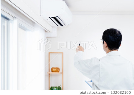 一名身穿工作服的男子正在檢查空調的運作情況 132082100