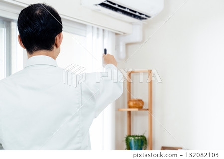 A man in work clothes checking the operation of an air conditioner A man in work clothes checking the operation of an air conditioner 132082103