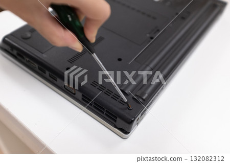 Hand holding screwdriver to repair laptop Hand holding screwdriver to repair laptop 132082312