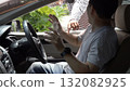 Masked thief threatening a driver through a car window during an attempted robbery. Concept of car crime, carjacking, danger, security awareness, and personal safety in urban environments 132082925
