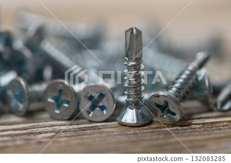 Pile of metal roofing screws on rustic wooden surface Pile of metal roofing screws on rustic wooden surface 132083285