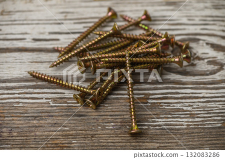 Bronze screws pile on old workshop table 132083286