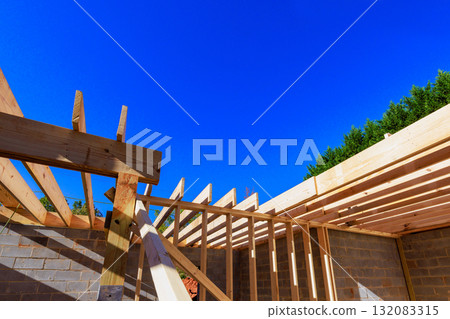 Construction workers frame wooden roof structure on building site with rafters structure beams 132083315