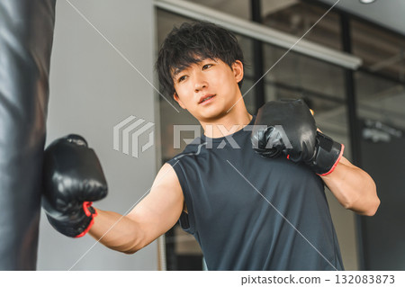 Gym, young Asian man punching a punching bag in training gym 132083873
