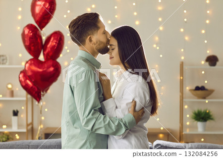 Handsome young man kissing woman forehead while she leaning into him Handsome young man kissing woman forehead while she leaning into him 132084256