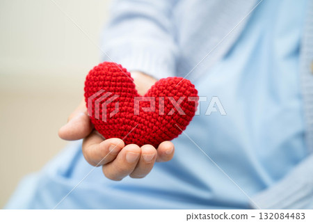 Asian elder senior woman patient holding red heart in hospital. 132084483