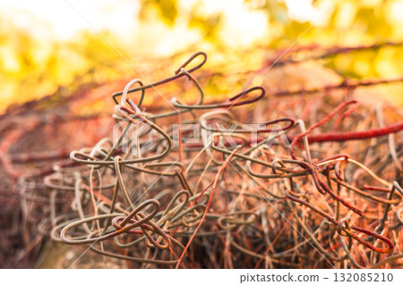 Close-up of rusty metal wire coil with soft warm bokeh background Close-up of rusty metal wire coil with soft warm bokeh background 132085210