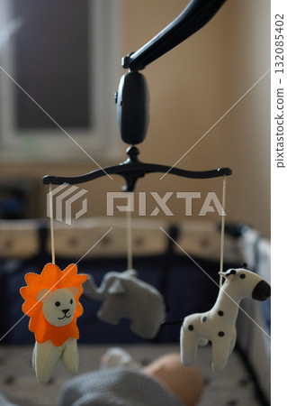 Colorful Animal Toys Hanging Above a Crib in a Cozy Nursery During Daytime Colorful Animal Toys Hanging Above a Crib in a Cozy Nursery During Daytime 132085402