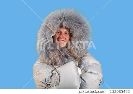 Woman in Winter Coat Points to Copy Space With a Smile on a Blue Background Woman in Winter Coat Points to Copy Space With a Smile on a Blue Background 132085403