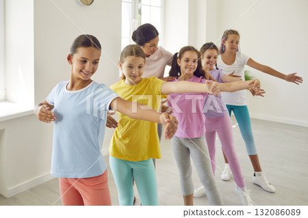 Woman choreographer helping her students girls in doing a dance exercises in studio. Woman choreographer helping her students girls in doing a dance exercises in studio. 132086089