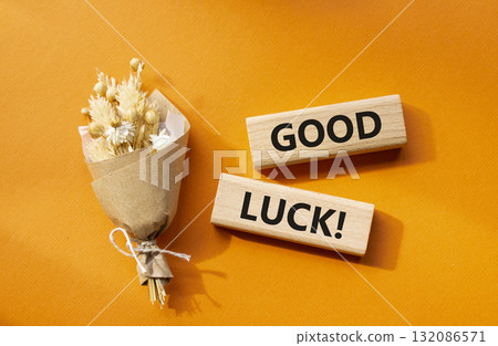 Good luck symbol. Wooden blocks with words Good luck. Beautiful orange background with bouquet of flowers. Business and Good luck concept. Copy space. 132086571