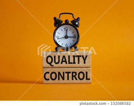 Quality Control symbol. Wooden blocks with words Quality Control. Beautiful orange background with alarm clock. Business and Quality Control concept. Copy space. 132086582