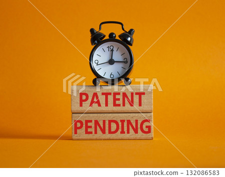 Patent Pending symbol. Wooden blocks with words Patent Pending. Beautiful orange background with alarm clock. Business and Patent Pending concept. Copy space. 132086583