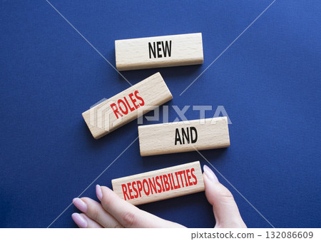 New roles and responsibilities symbol. Wooden blocks with words New roles and responsibilities. Beautiful deep blue background. Businessman hand. Business concept. Copy space. 132086609