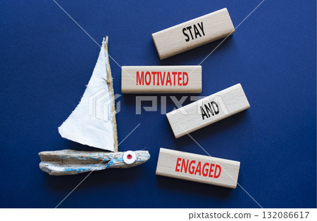 Stay Motivated and Engaged symbol. Concept words Stay Motivated and Engaged on wooden blocks. Beautiful deep blue background with boat. Business concept. Copy space Stay Motivated and Engaged symbol. Concept words Stay Motivated and Engaged on wooden blocks. Beautiful deep blue background with boat. Business concept. Copy space 132086617
