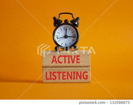 Listen actively symbol. Wooden blocks with words Listen actively. Beautiful orange background with alarm clock. Business and Active listening concept. Copy space. 132086673